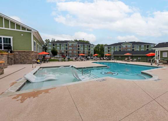 A large outdoor swimming pool surrounded by a patio and umbrellas at Foxwood Apartments, Raleigh-Durham, 27616