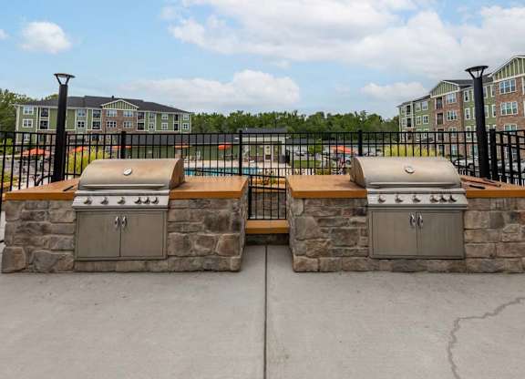 Two stone BBQs are in front of a black fence at Foxwood Apartments, Raleigh-Durham, North Carolina
