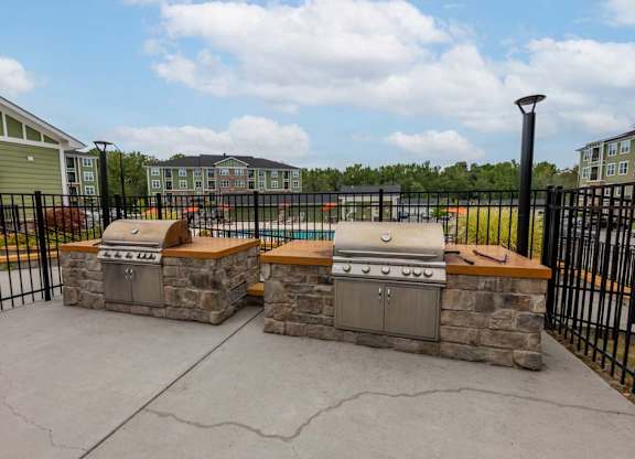 A stone fireplace with a grill on top is in the middle of a concrete patio at Foxwood Apartments, Raleigh-Durham, NC