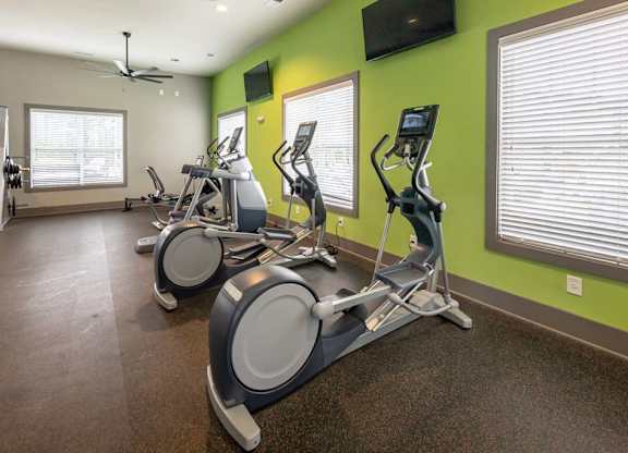 A gym with exercise bikes and a television on the wall at Foxwood Apartments, North Carolina, 27616