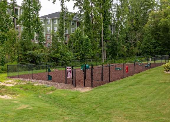 A green lawn with a fence and a sign at Foxwood Apartments, Raleigh-Durham, 27616