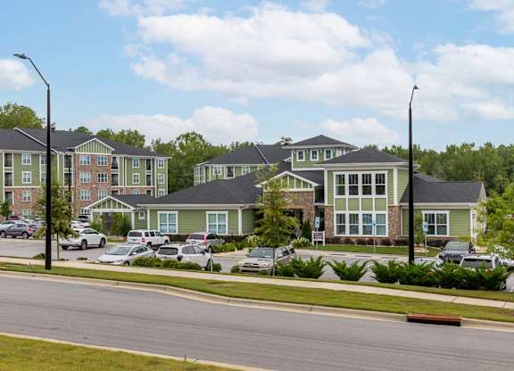 Apartment complex with green and brown buildings and cars parked in front at Foxwood Apartments, Raleigh-Durham, North Carolina
