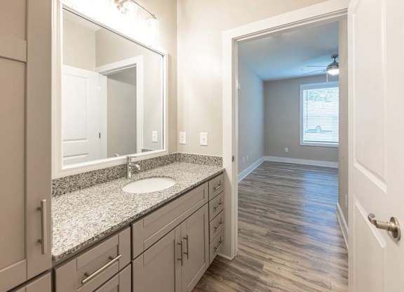 A bathroom with a sink, mirror, and wooden floors at Foxwood Apartments, North Carolina
