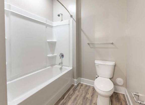 A white toilet sits next to a bathtub in a bathroom at Foxwood Apartments, North Carolina, 27616