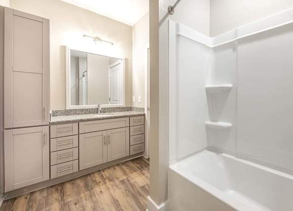 A white bathroom with a wooden floor and a white bathtub at Foxwood Apartments, Raleigh-Durham, NC