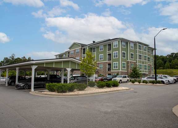 A parking lot in front of a green building at Foxwood Apartments, Raleigh-Durham, NC, 27616