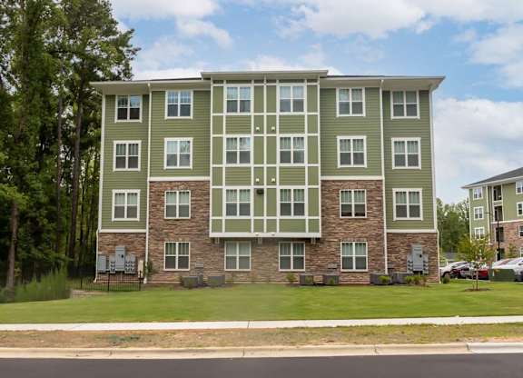 A large apartment building with a green and grey exterior at Foxwood Apartments, North Carolina, 27616