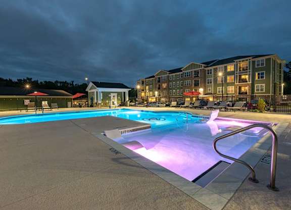 A lit up pool at night with a building in the background. at Foxwood Apartments, North Carolina, 27616