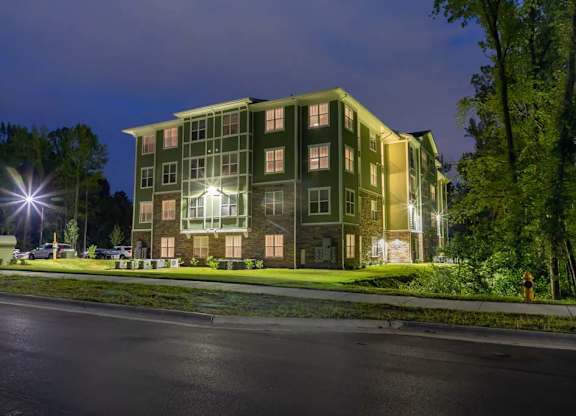 A large building with a greenish hue is illuminated at night at Foxwood Apartments, Raleigh-Durham, North Carolina