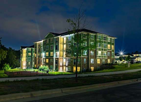 A large green building with lights on at night. at Foxwood Apartments, Raleigh-Durham, 27616