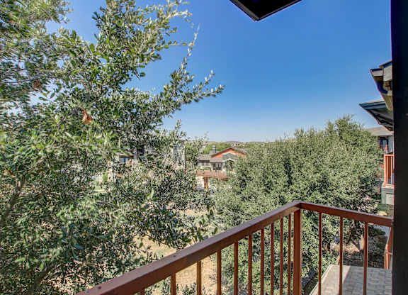 A balcony with a railing overlooks a tree-filled landscape.