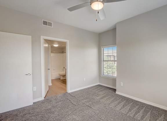 A room with a ceiling fan and carpeted floor.