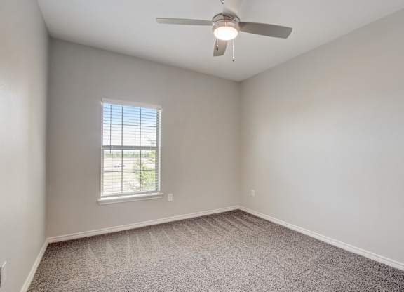 A room with a ceiling fan and carpeted floor.