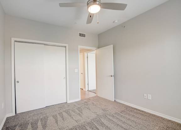 A room with a ceiling fan and carpeted floor.