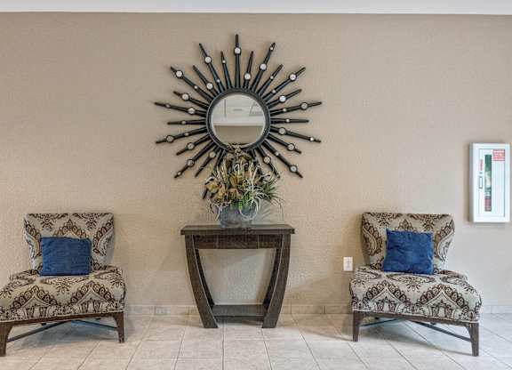 Two chairs and a table with a mirror above it.