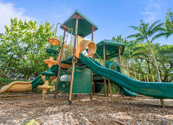 A playground with a green slide and a wooden structure.