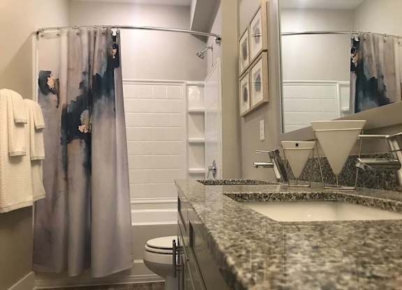 A bathroom with a marble counter top and a shower curtain. at Foxwood Apartments, Raleigh-Durham, NC