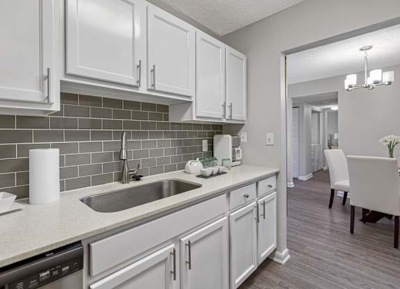 A kitchen with white cabinets and a grey backsplash.