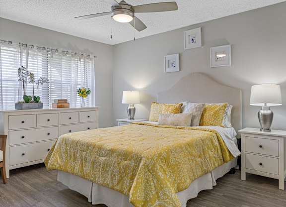 A bedroom with a bed, nightstands, and a ceiling fan.
