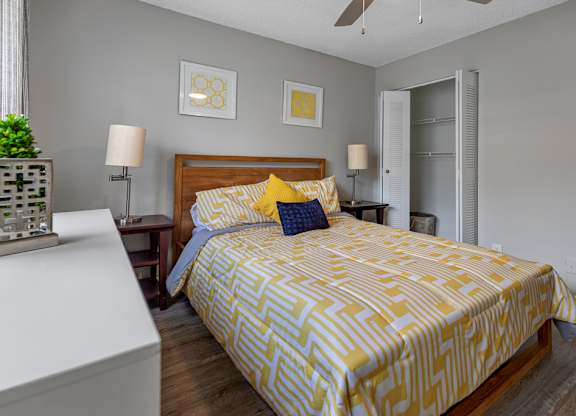 A bed with a yellow and white comforter is in the center of the image.