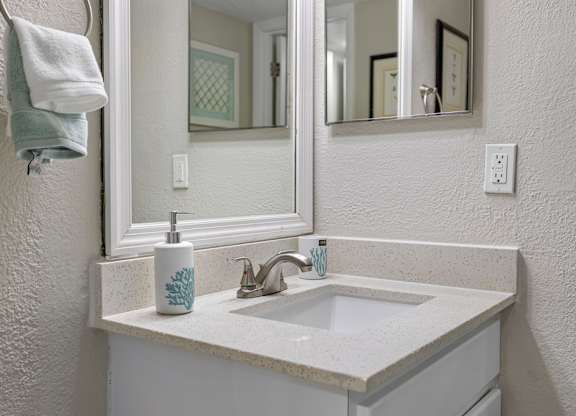 A white sink with a blue and white soap dispenser on a counter.