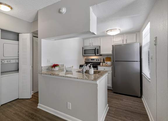 A kitchen with a refrigerator, microwave, and oven.