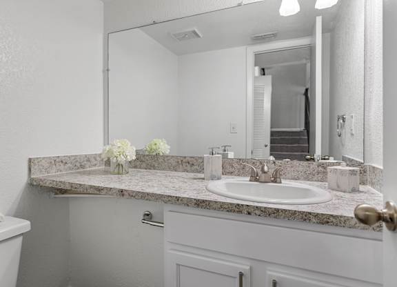 A bathroom with a marble countertop and a white sink.