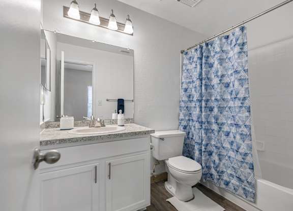 A white bathroom with a blue shower curtain.