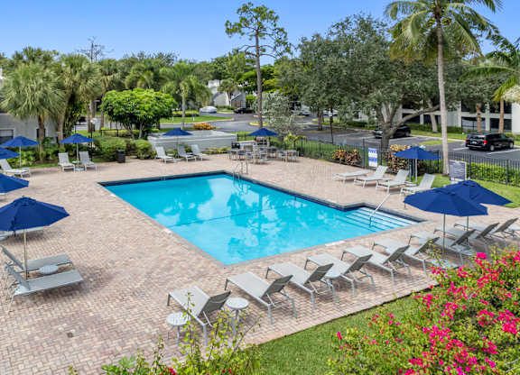 A pool surrounded by lawn chairs and umbrellas.