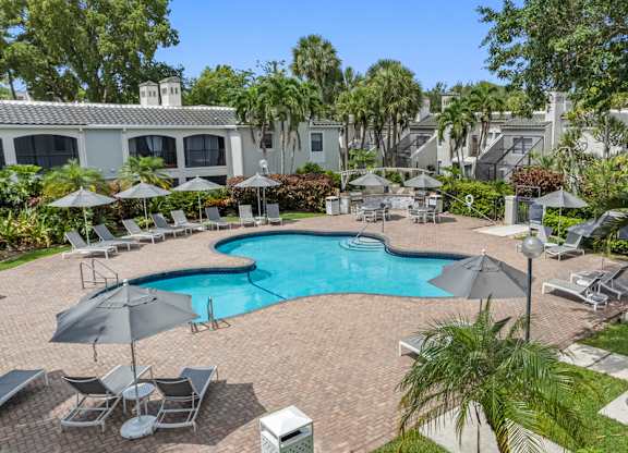 A pool surrounded by chairs and landscaping.