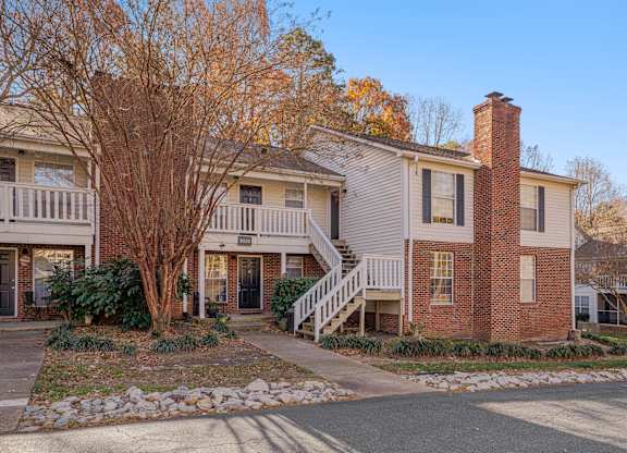 A house with a brick chimney and a tree with no leaves.
