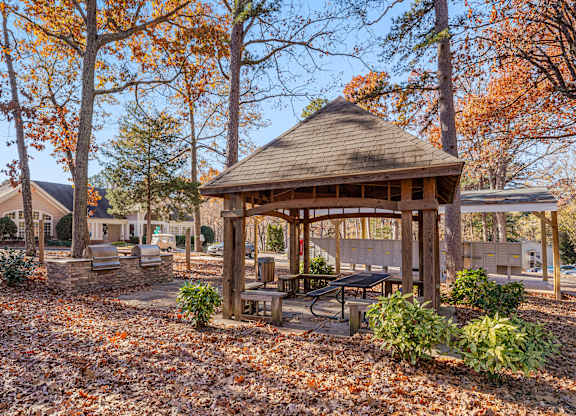 A gazebo surrounded by trees with orange leaves.
