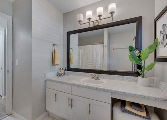 A bathroom with a sink, mirror, and cabinets.