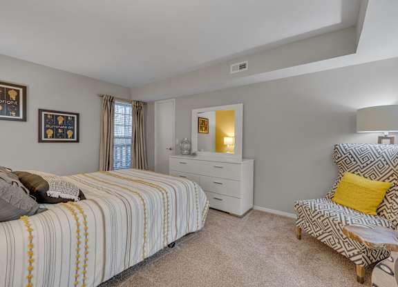 A bedroom with a bed, chair, and nightstand.