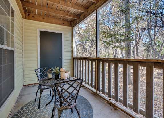 A small table with two chairs is on a porch.