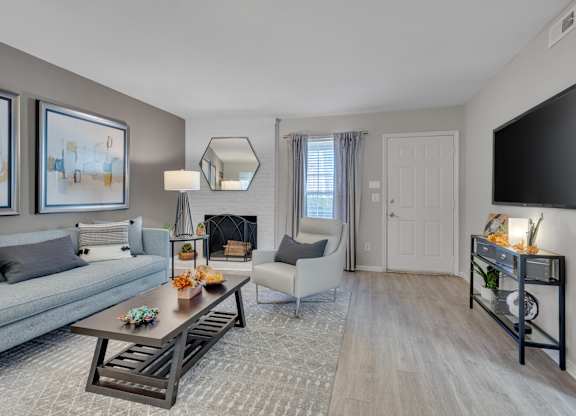 A living room with a grey couch, a coffee table, and a fireplace.
