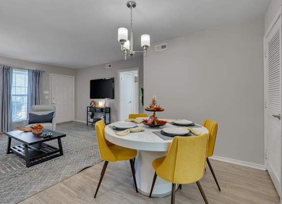 A dining room with a white table and yellow chairs.