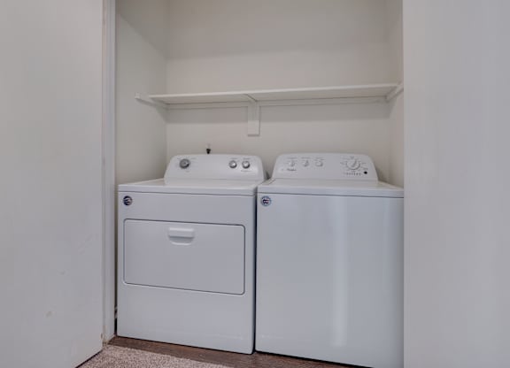 Two white front loading washing machines in a small laundry room.