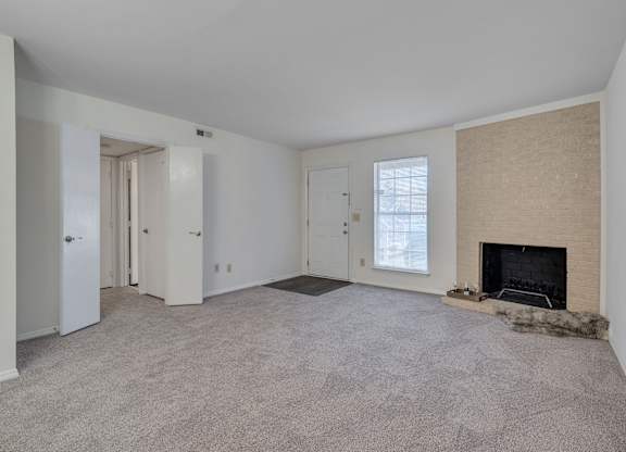 A living room with a fireplace and carpeted floor.