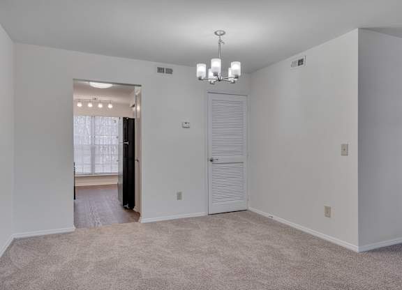 A large, empty room with a carpeted floor and a chandelier hanging from the ceiling.