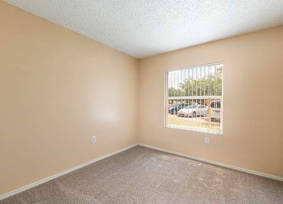 A room with a window showing a parking lot outside.