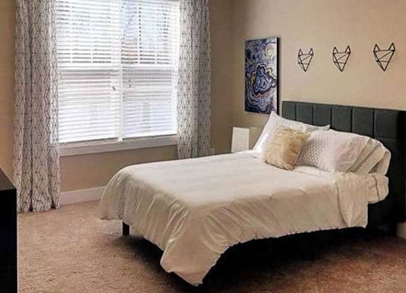 A bedroom with a bed, pillows, and a window with curtains at Foxwood Apartments, Raleigh-Durham, NC, 27616
