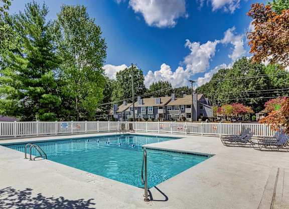 A large swimming pool surrounded by trees and a fence. at Brandemere Apartment Homes, Winston Salem, NC, 27106
