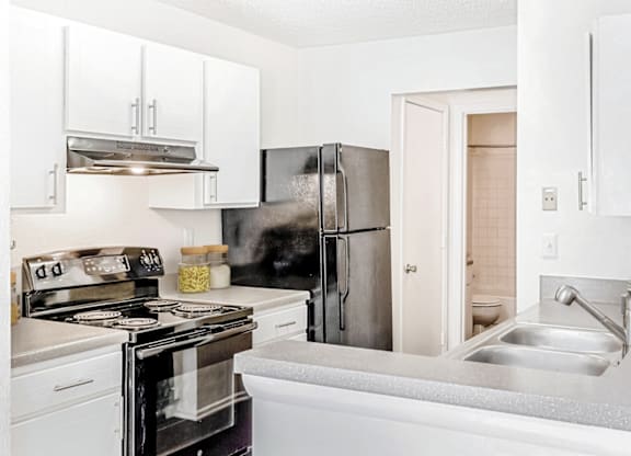 a kitchen with white cabinets and stainless steel appliances at Bridges at Mallard Creek Apartment Homes, North Carolina