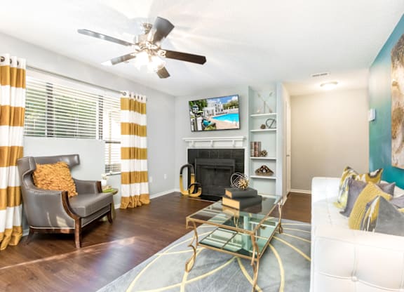 a living room with a fireplace and a ceiling fan at Bridges at Mallard Creek Apartment Homes, Charlotte, NC, 28269