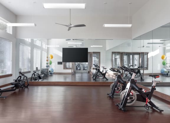 a workout room with exercise bikes and a tv