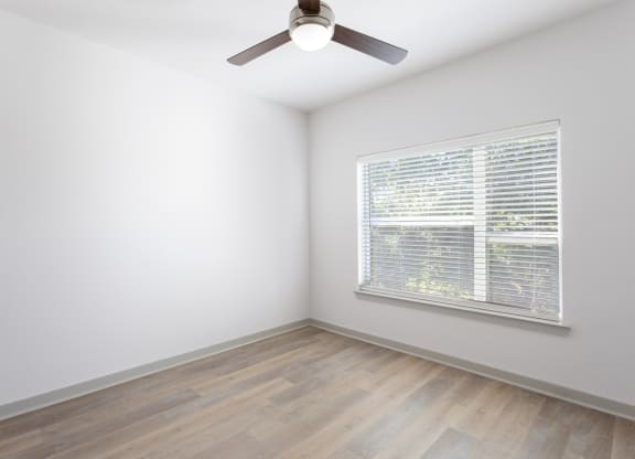 a bedroom with a large window and wood flooring