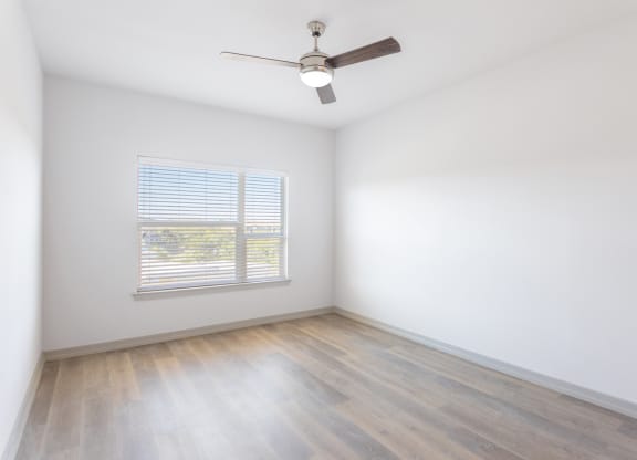 an empty room with white walls and wood floors and a ceiling fan