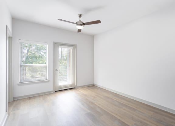 an empty living room with white walls and a ceiling fan