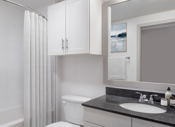a bathroom with white cabinets and black countertop